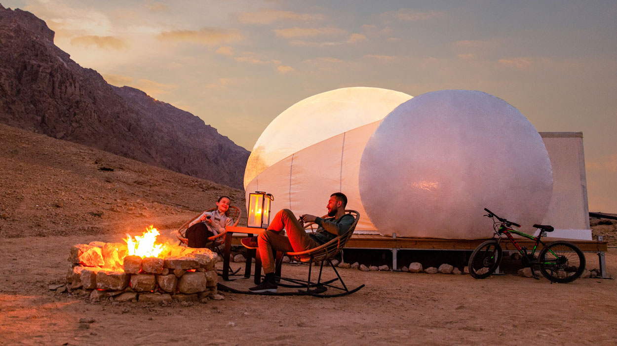 Bubble tent camping with a fire pit and mountain view