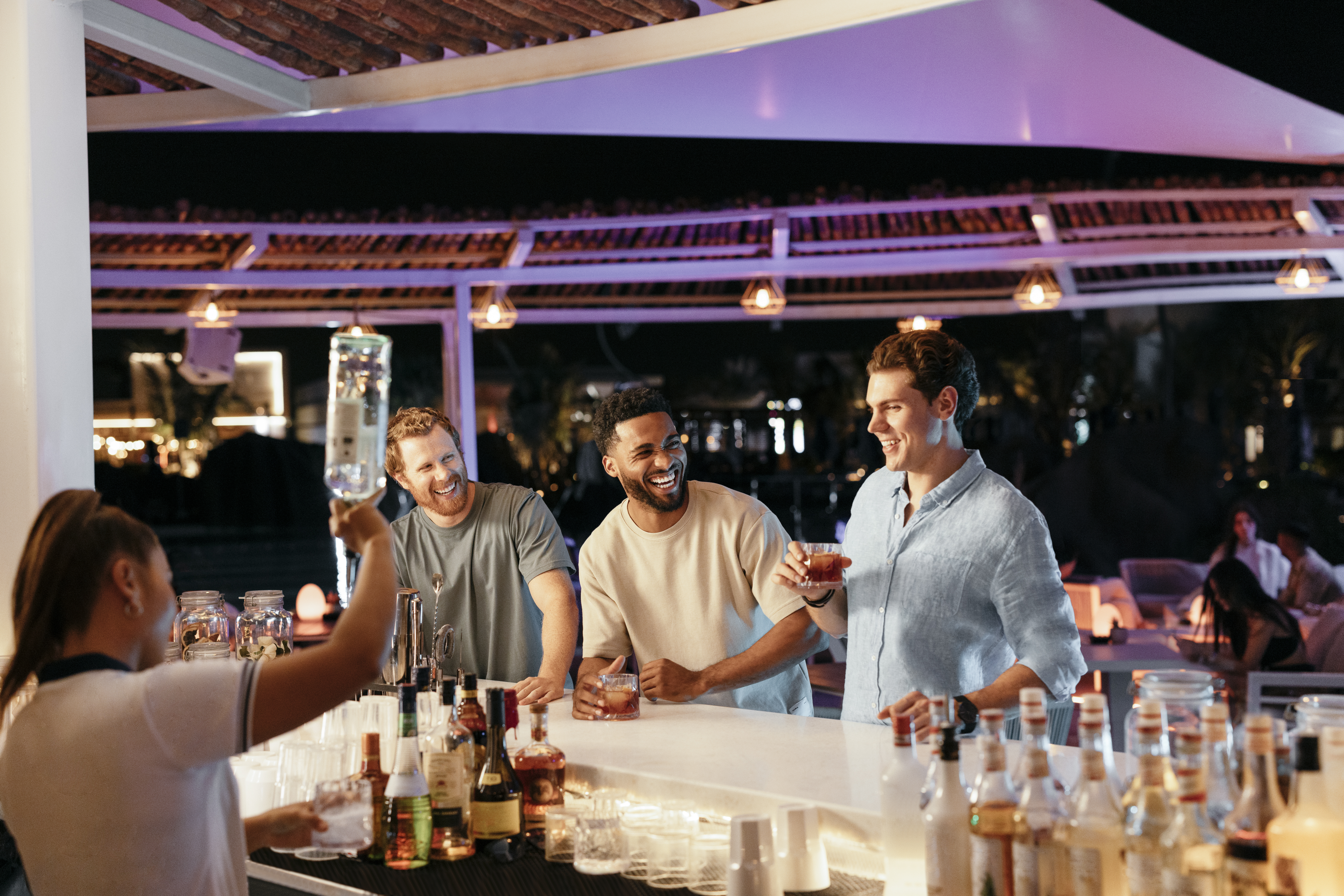 Friends enjoying cocktails at a stylish rooftop bar in Abu Dhabi, with a lively nighttime ambiance.