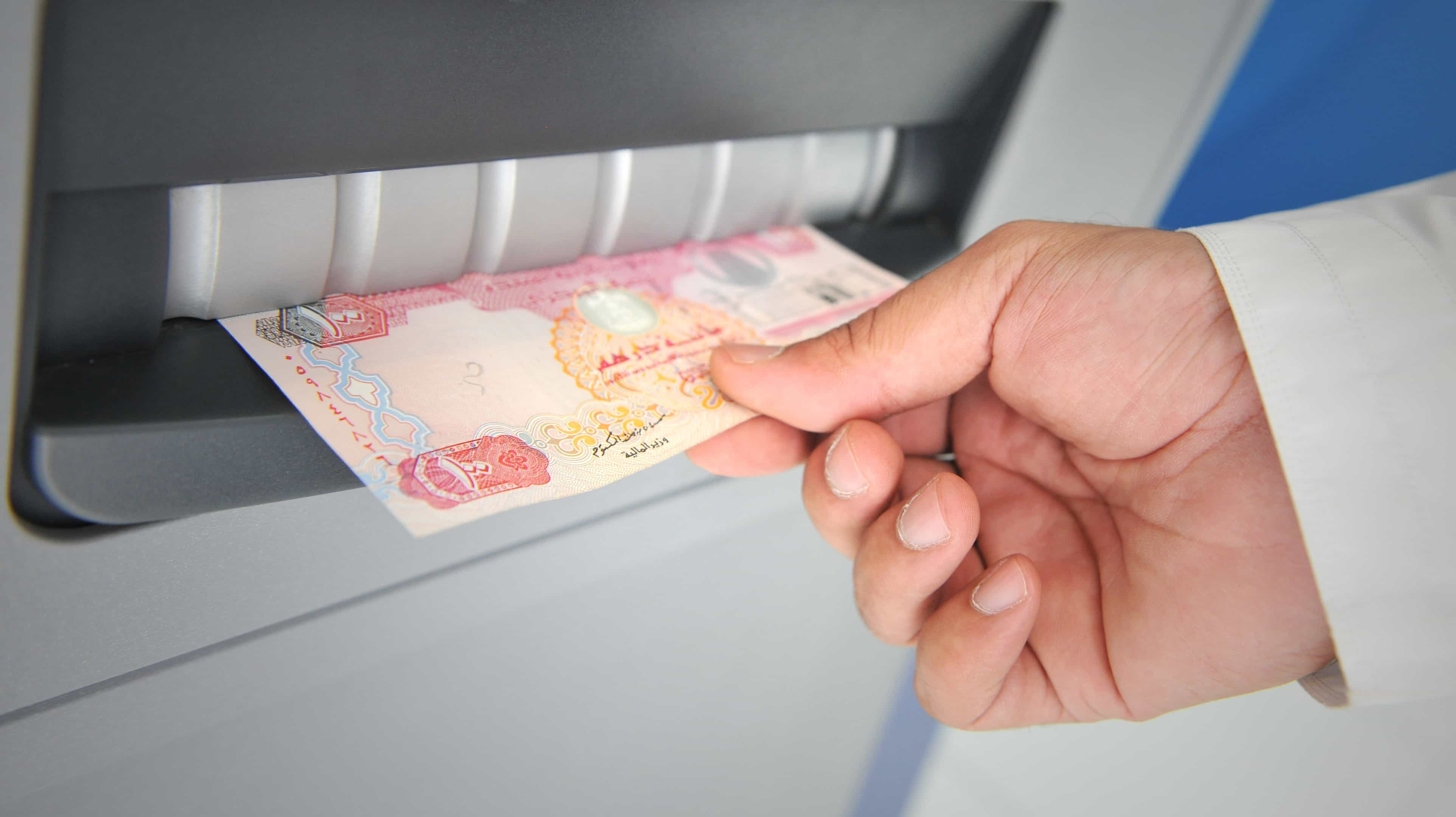 Si vede la mano di un uomo. Lui preleva denaro da un bancomat