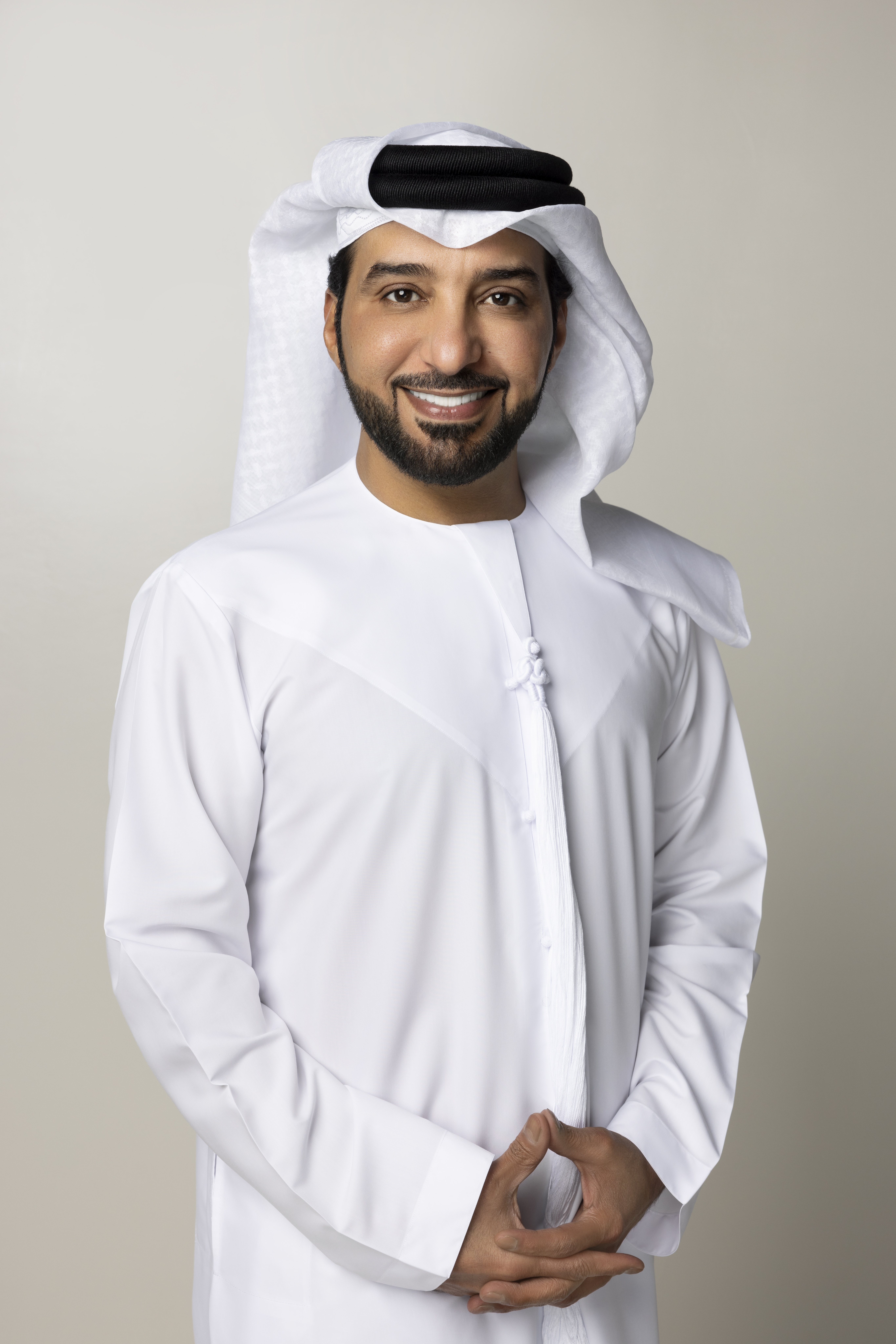 Emirati man in traditional white kandura smiling confidently against a neutral background